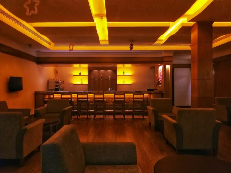 Empty hotel lounge bar at night, amber cove lighting, armchairs and a row of bar stools