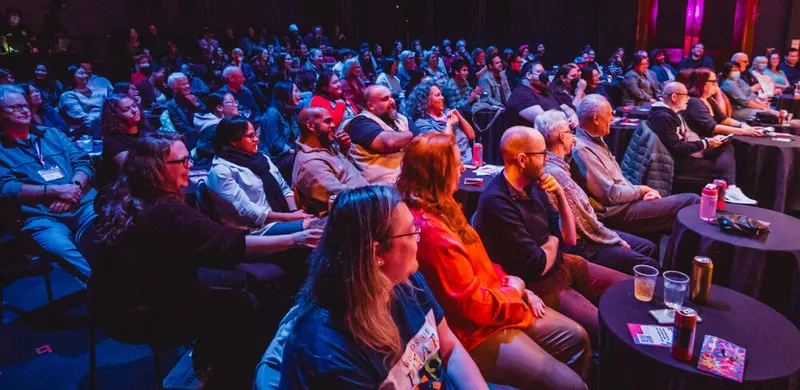 A laughing audience at cabaret tables during Comedy is Art 2024 at The Theatre Centre
