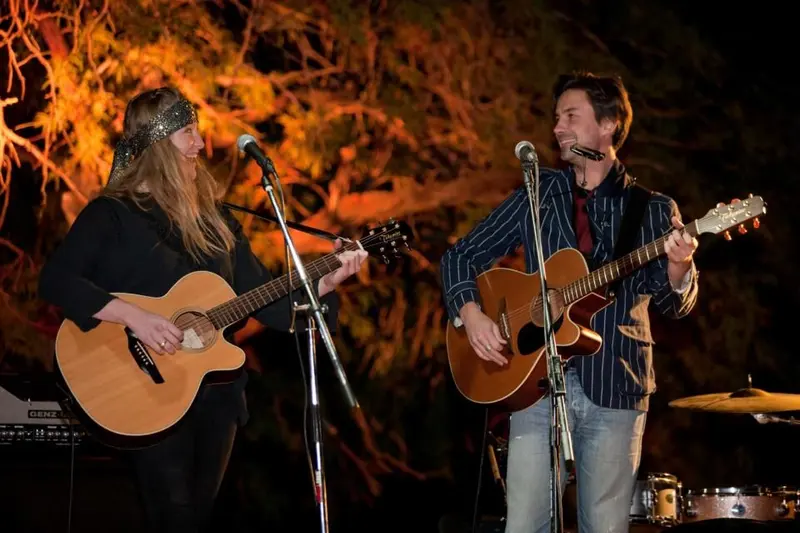 Two musicians playing acoustic guitars on the outdoor stage at The Palms in Wonder Valley, the desert bar that hosts the