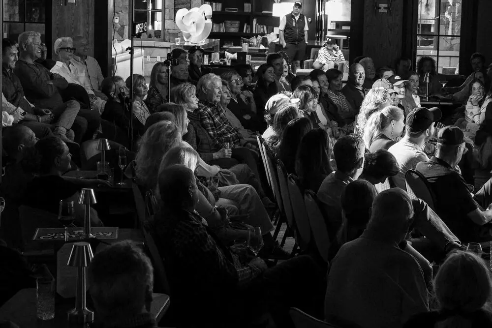 A black-and-white view over a full house of seated guests watching a Mountain Fresh Comedy Festival show
