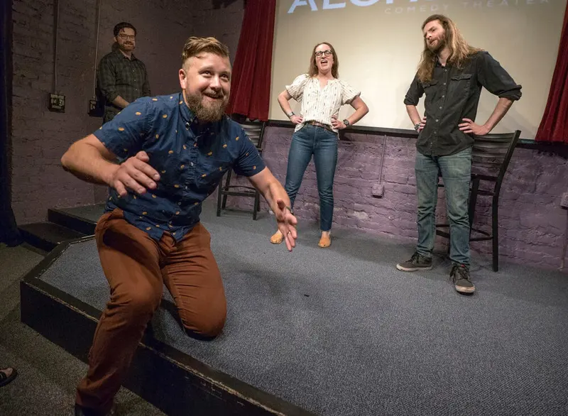 Improv performers mid-scene on the stage of the Alchemy Comedy Theater in Greenville, the home of the New South Comedy
