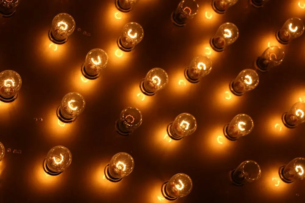 A field of bare amber marquee bulbs glowing on a dark panel, no letters
