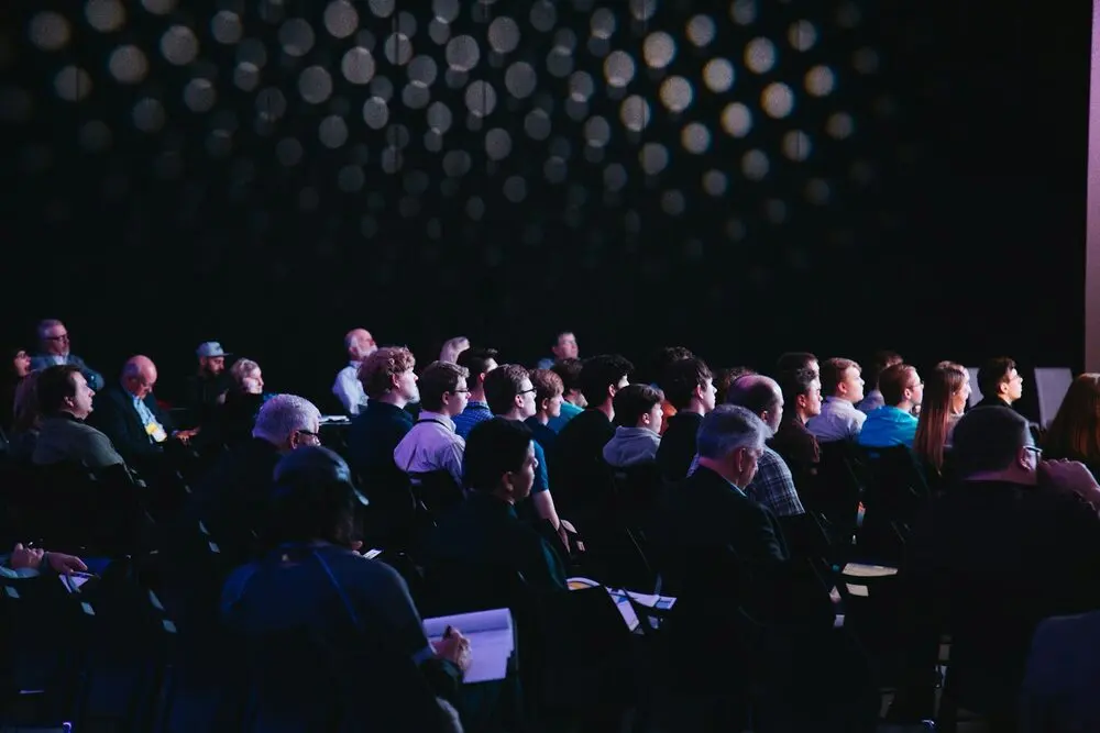Conference audience in a dark hall, bokeh wall